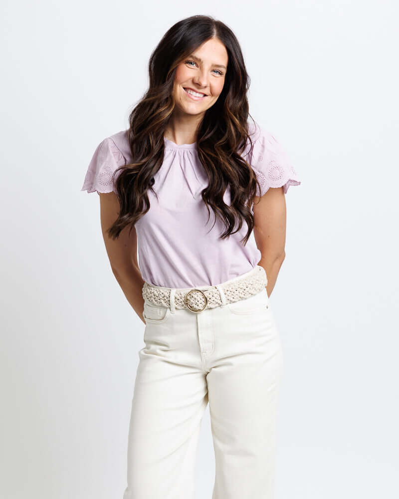 Lovely Eyelet Tee from Downeast in lilac with eyelet sleeves, paired with cream pants and a styled belt.