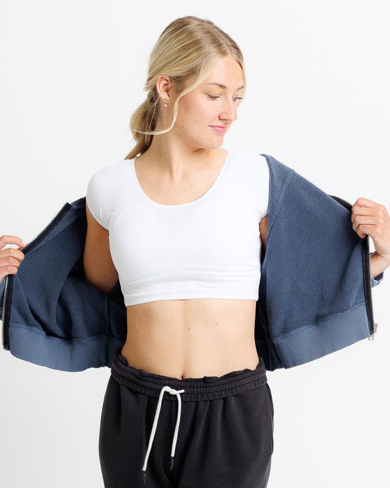 Model wearing a white cropped tee under an open blue jacket, showcasing a relaxed, layered style.
