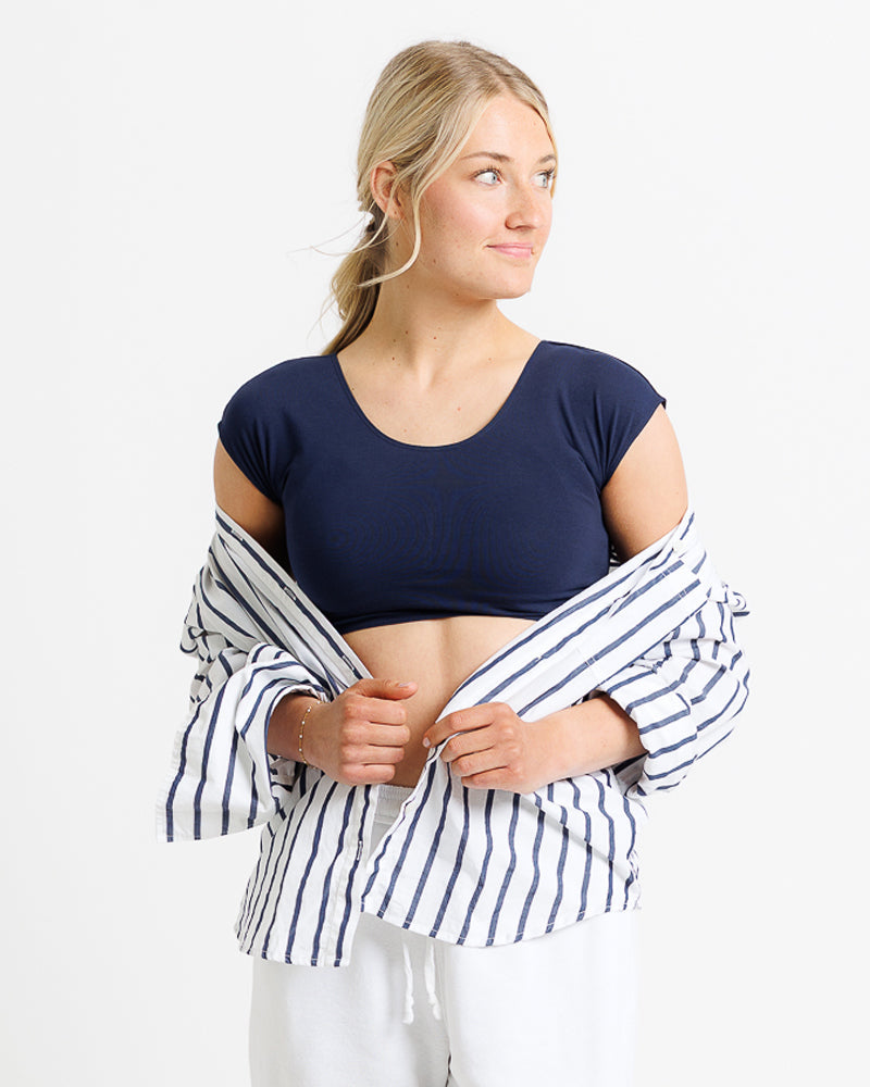 Model wearing Downeast Demi Tee in navy with cropped cap sleeves, styled with a striped shirt.